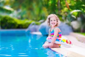 Little girl smiling with floaty on edge of pool
