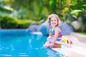 Little girl smiling with floaty on edge of pool