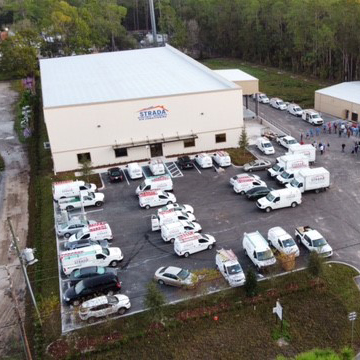 A bird view of Strada Services building and parking lot. There is a group of people in the parking lot.