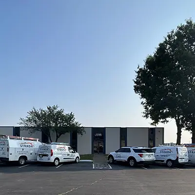 A front view of Strada Services headquarters building. Strada Services vehicles are parked in front of the building.