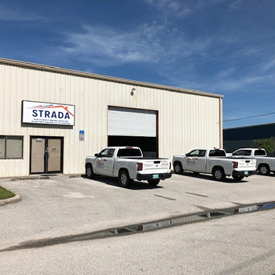A front view of a Strada Services building. Strada Services pickup trucks are parked in front of the building.