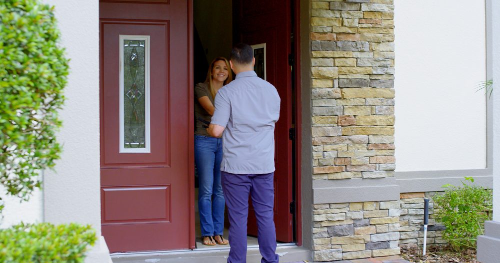 Homeowner greeting service technician at front door