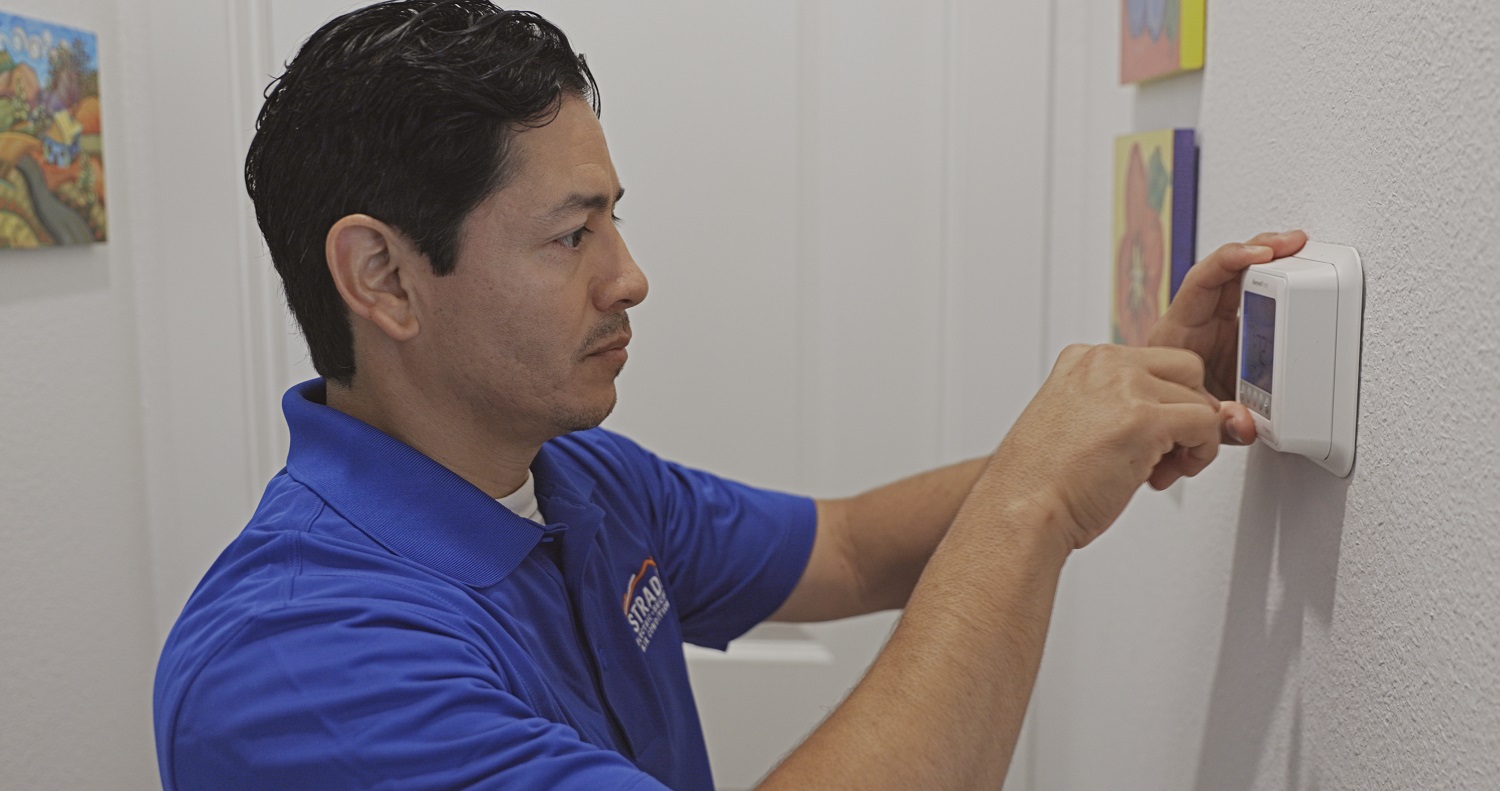 Strada Service Technician performing heating and cooling services by fixing thermostat