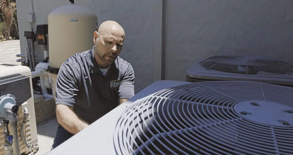 Técnico de servicio de Strada trabajando en la reparación de un sistema de calefacción, ventilación y aire acondicionado