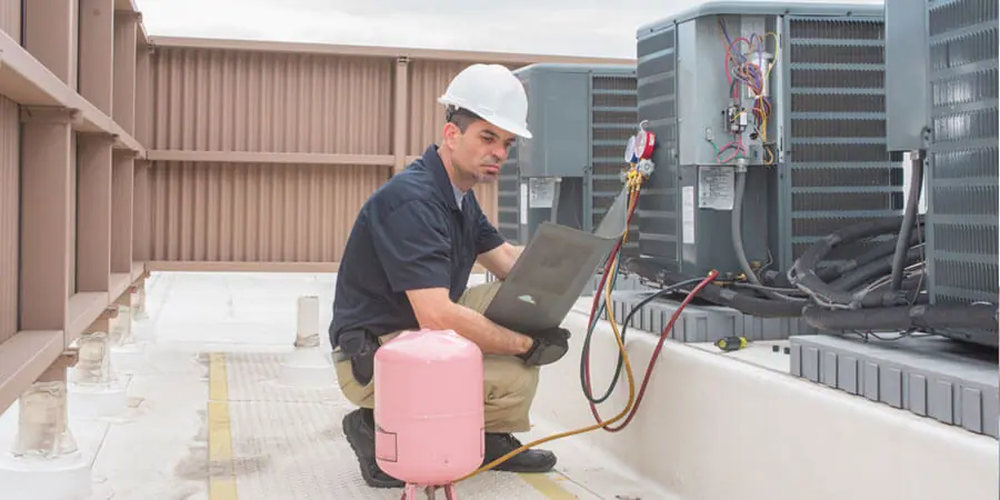 Técnico de Strada Services trabajando en un sistema de aire acondicionado comercial