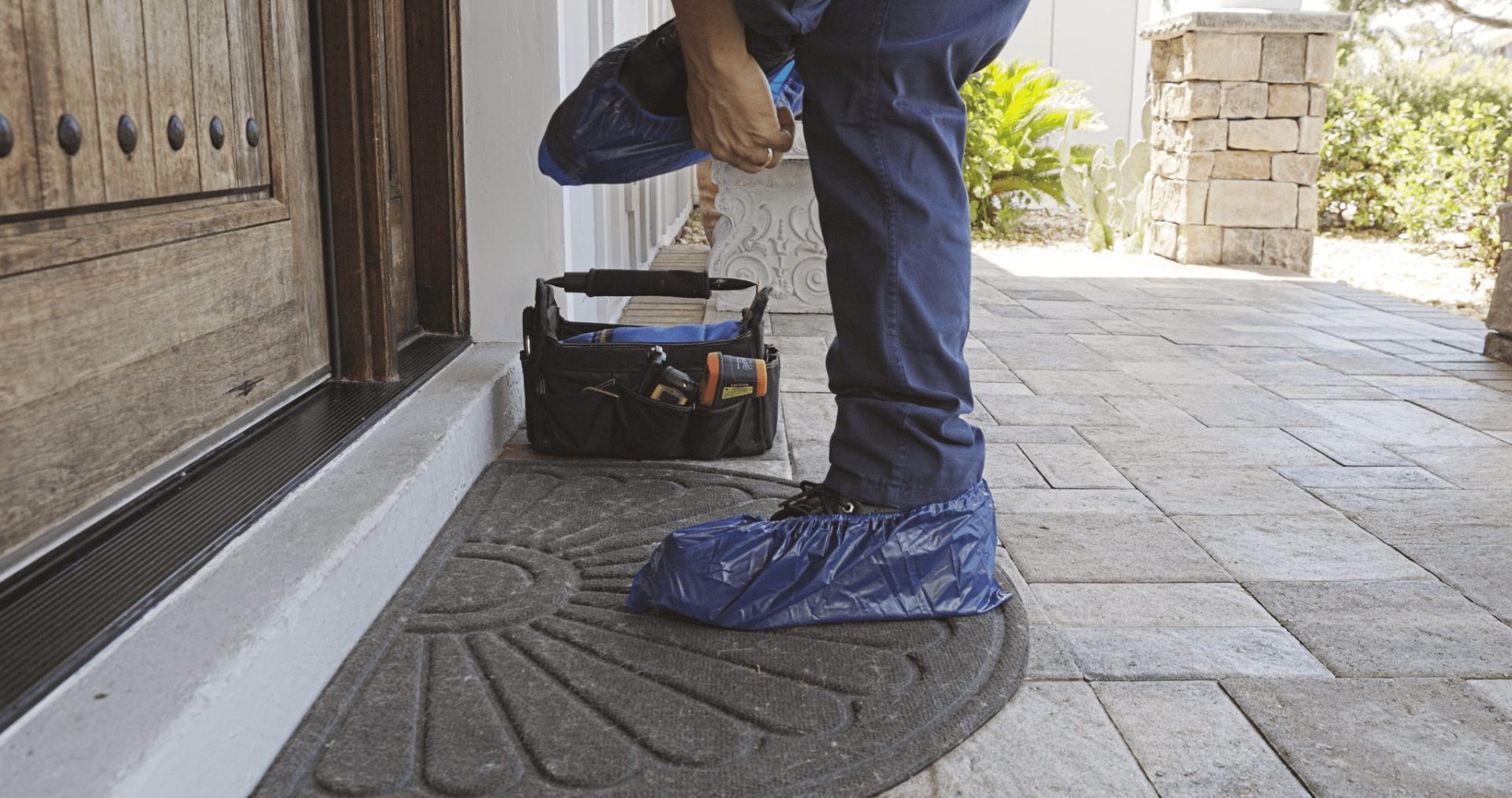 Service technician putting on work shoe covers before going into house