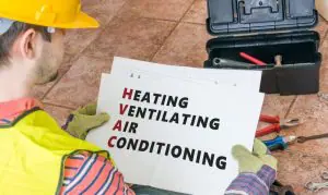 Workman holding signs that says Heating Ventilating Air Conditioning