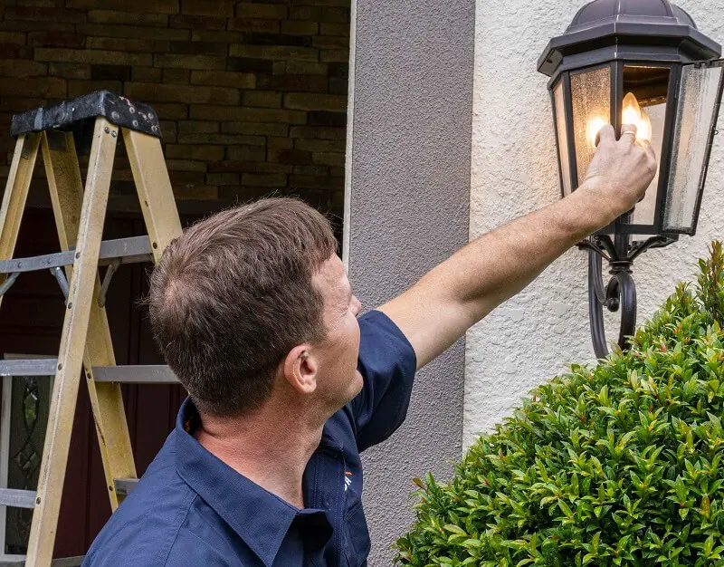 Strada employee providing electrical services by checking outdoor light fixture